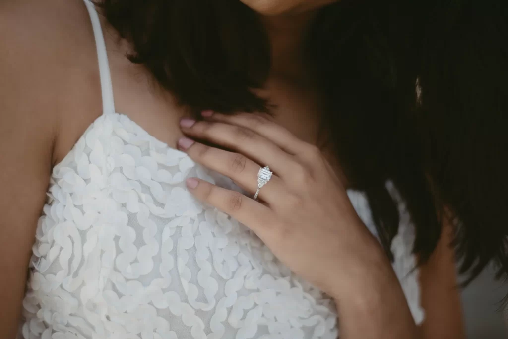 Woman in wedding dress holding up her hand with a diamond ring on her finger.